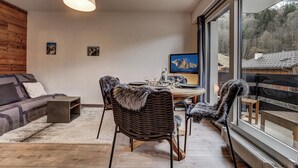 En moderne stue med spiseplads, store vinduer og udsigt over det fri.