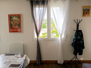 Een kamer met een bed, een raam met gordijnen, een kapstok en een poster aan de muur.