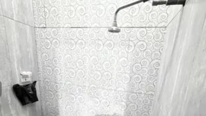 Un baño con inodoro, ducha y pared con diseño.