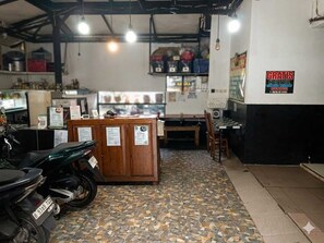 Una habitación con piso de baldosas, una recepción, una motocicleta y un cartel que indica hotel gratuito.