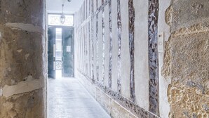 A corridor with stone walls and a tiled floor, leading to a door at the end. - 2066 Princesse (Paris)