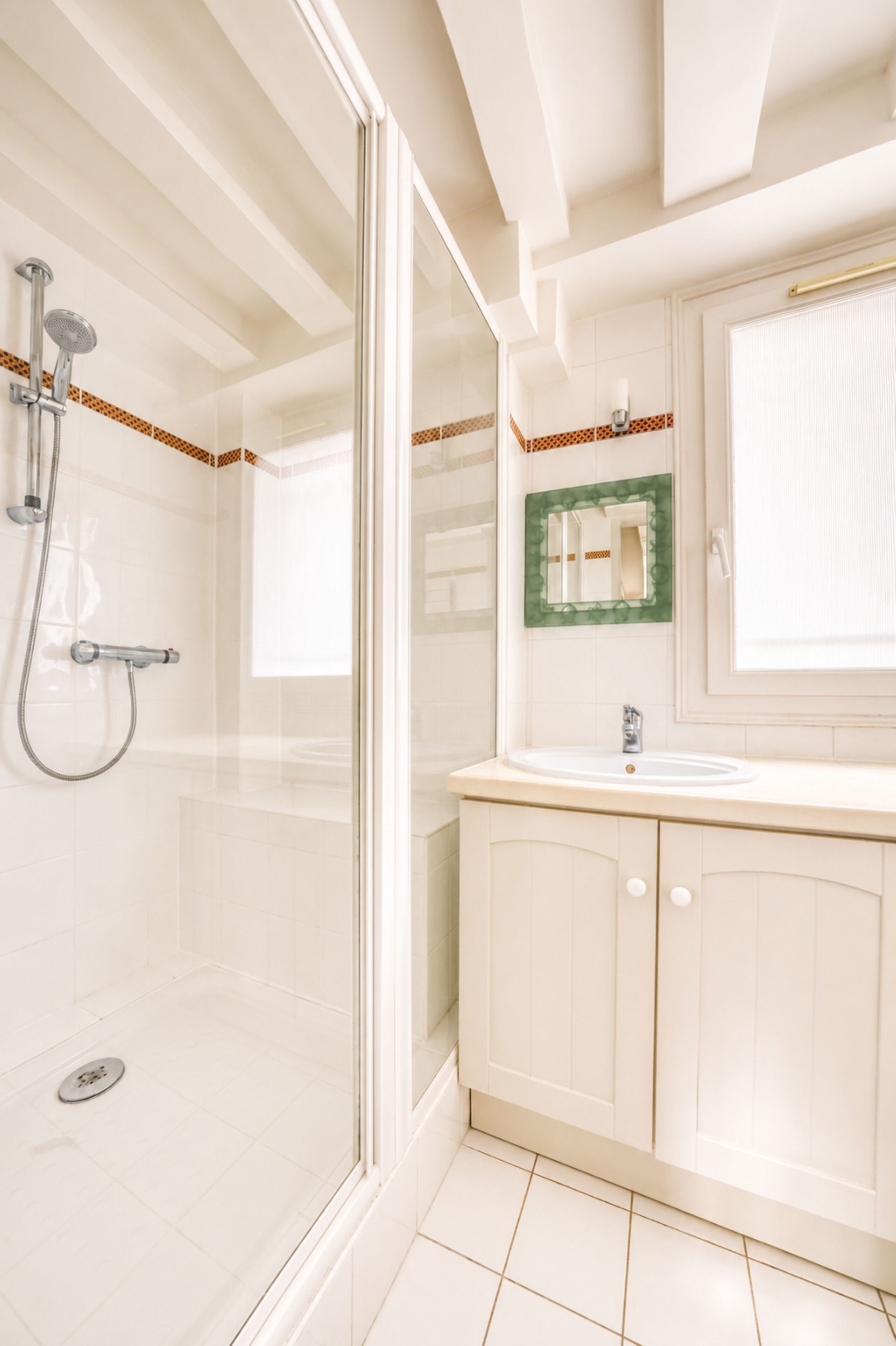 Ein Badezimmer mit Duschkabine aus Glas, Waschbecken mit Spiegel und Schrank.