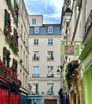 A narrow street with buildings on either side, some with balconies and flower boxes. - 2066 Princesse (Paris)