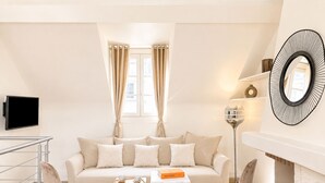 A modern living room with a sofa, two chairs, a coffee table, a flat-screen TV, a floor lamp, and a fireplace. - 2066 Princesse (Paris)