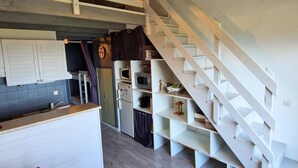 A modern kitchen with a built-in staircase, white cabinetry, and a hanging light fixture. - Duplex for 6, pets allowed, south balcony, Chaillol 1600 (Saint-Michel-de-Chaillol)