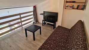 A living room with a sofa, a TV, and a small table. There is a window with a view outside. - Duplex for 6, pets allowed, south balcony, Chaillol 1600 (Saint-Michel-de-Chaillol)