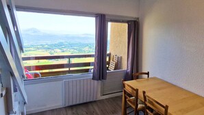 A balcony with a wooden table and chairs, a view of the countryside, and a window with curtains. - Duplex for 6, pets allowed, south balcony, Chaillol 1600 (Saint-Michel-de-Chaillol)