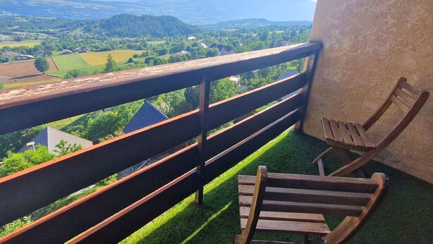 A balcony with a wooden railing, two wooden chairs, and a view of a green landscape with fields and distant mountains. - Duplex for 6, pets allowed, south balcony, Chaillol 1600 (Saint-Michel-de-Chaillol)