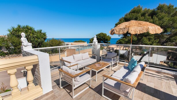 Een terras met tuinmeubilair, een standbeeld en uitzicht op zee.