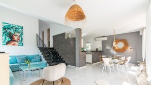 Een moderne woonkamer met een bank, salontafel en een eethoek met stoelen en een tafel.