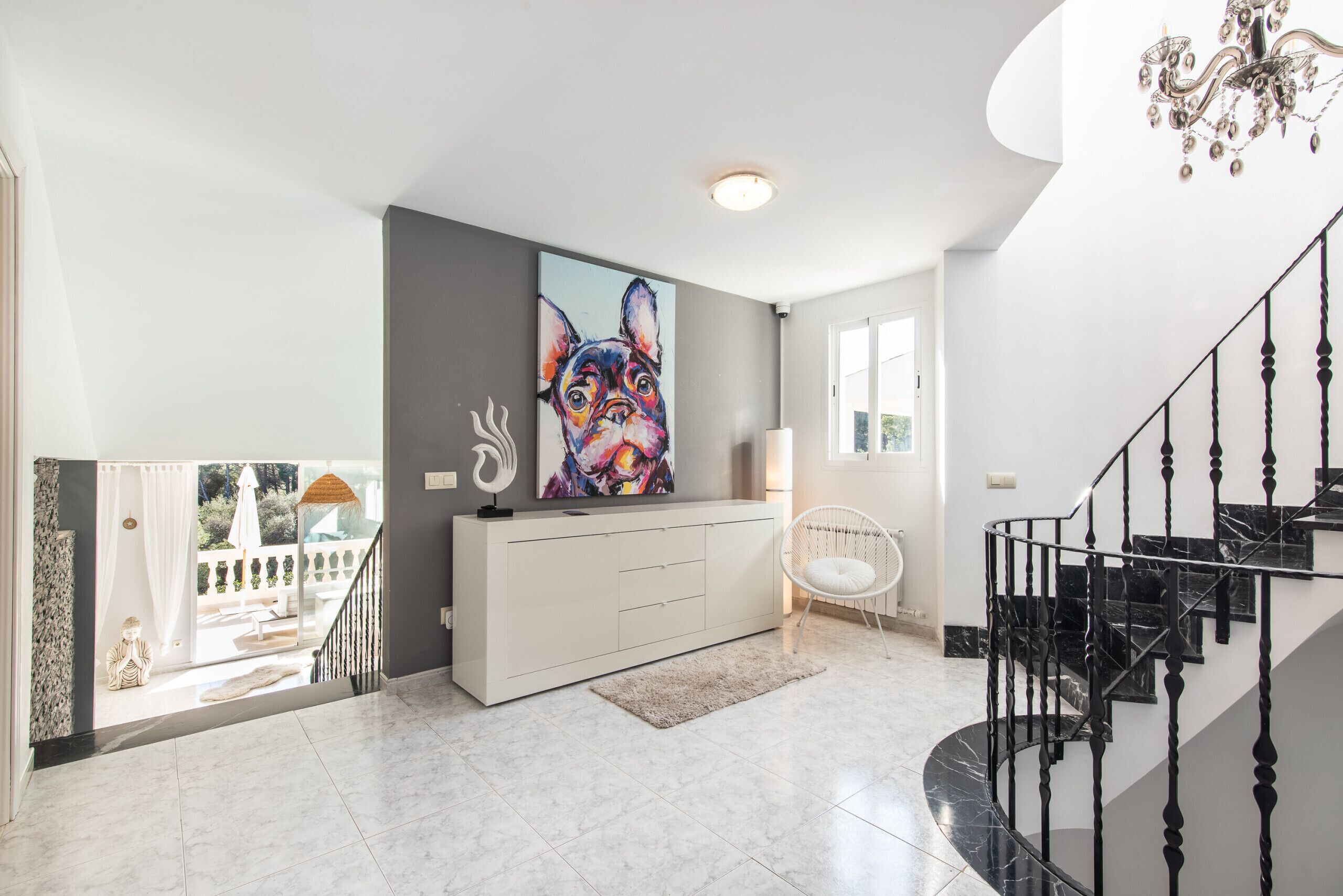 Un interno moderno con una scala, un tavolino consolle bianco e un quadro di grandi dimensioni.