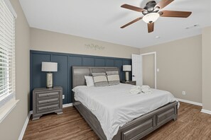 A bedroom with a bed, nightstands, a ceiling fan, and a window with blinds.