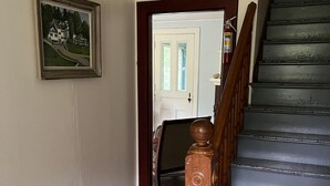 A wooden staircase with a handrail, a door leading to another room, and a framed picture on the wall. - Mountain cottage. 4-bdrm cottage in the White Mountains with hiking trails. (Shelburne)