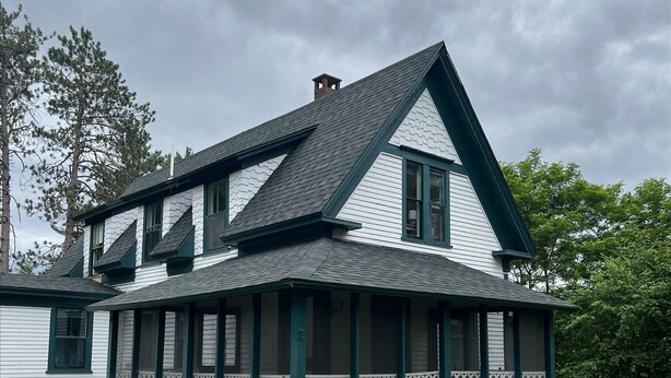 A two-story house with a gabled roof and a covered porch. - Mountain cottage. 4-bdrm cottage in the White Mountains with hiking trails. (Shelburne)