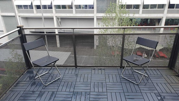 Un balcone con due sedie nere e una ringhiera in metallo.