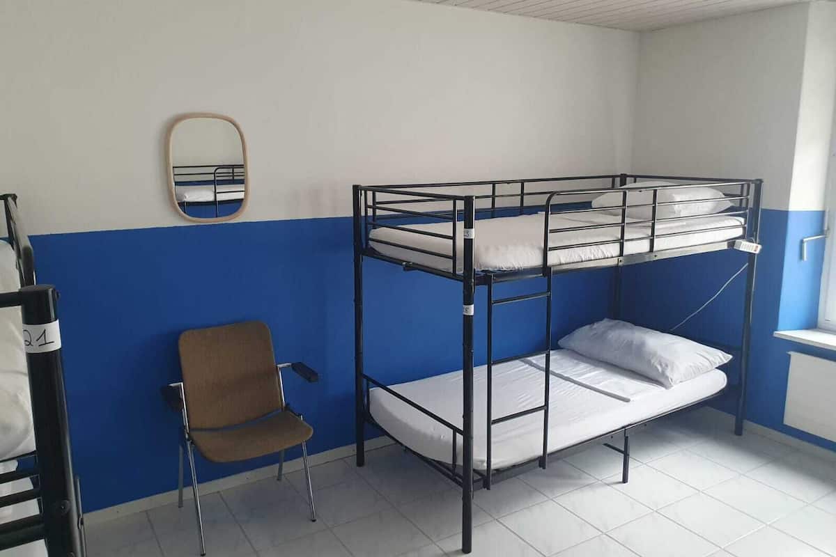 Habitación con literas, una pared azul, una silla y una ventana.