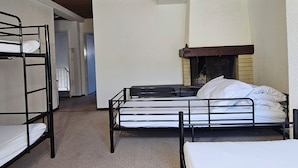 Una camera del dormitorio con letti a castello, un camino e un soffitto in legno.