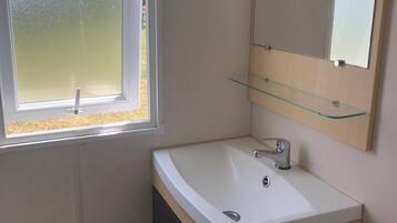 A bathroom with a white sink, a mirror, and a window.