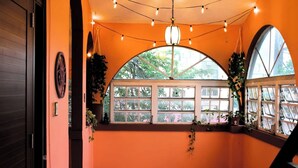 Un pasillo con un ventanal curvo, luces colgantes y plantas en macetas.