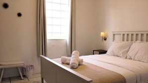 Un dormitorio con una cama, una mesita de noche, una lámpara y una ventana.