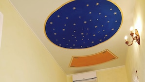 Une chambre à coucher comprenant un lit, un appareil de climatisation, une porte en bois et un mur agrémenté d’un plafond décoratif.