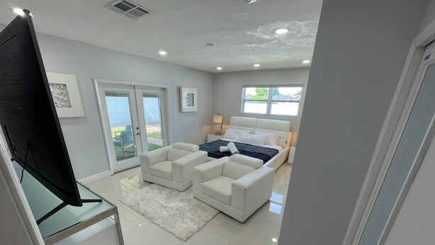 A modern bedroom with a large bed, a sofa, and a TV.