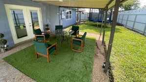 A covered patio area with a table and chairs, a door, and a fenced yard.