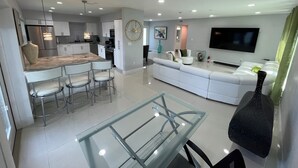 A modern kitchen with white cabinets, a marble countertop, and stainless steel appliances.