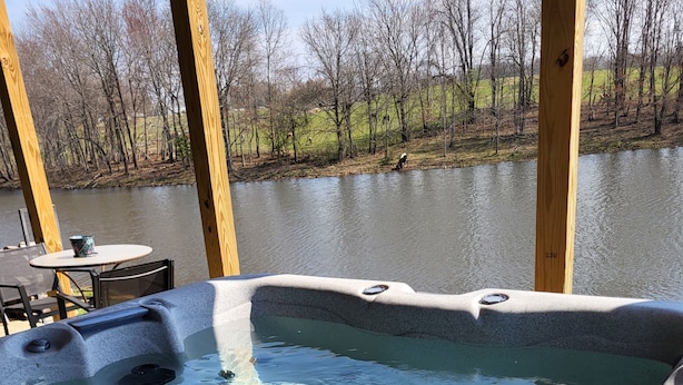 A hot tub with a view of a lake and trees.