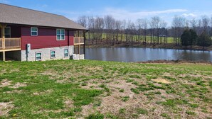 A two-story building with a balcony, a pond, and a grassy area.