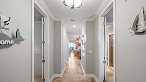 A hallway with a tiled floor, white walls, and a 'Welcome' sign on the left. - Fall Deals + Snowbird Rates | Ocean Views + Beach Getaway (Flagler Beach)