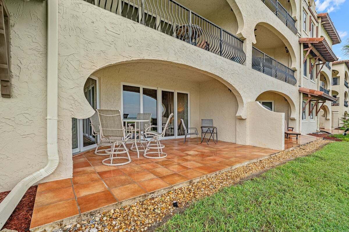 A multi-story building with a covered patio area featuring outdoor furniture.