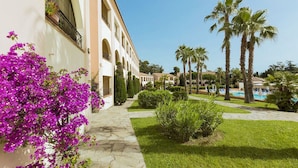 Un patio con piscina, palmeras y un edificio con arcos.