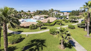 Un resort con piscina, palmeras y vista al océano.
