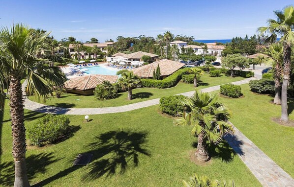A resort with a swimming pool, palm trees, and a view of the ocean.