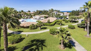Un resort con piscina, palmeras y vista al océano.