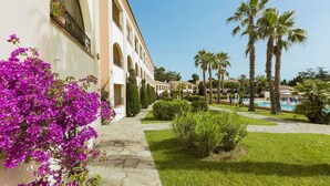 Un patio con piscina, palmeras y un edificio con arcos.