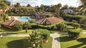 A resort with a swimming pool, palm trees, and a well-maintained garden.