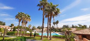 Un complexe hôtelier doté de palmiers, d’une piscine et de plusieurs bâtiments aux toits recouverts de tuiles rouges.