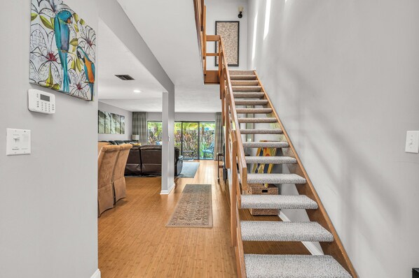 Un interior moderno con una escalera de madera, una sala de estar con sofá y vistas al exterior.