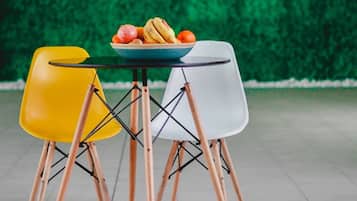 Een tafel met een schaal fruit en twee stoelen met houten poten.