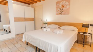 Une chambre d’hôtel avec un grand lit, deux lampes de chevet, une tête de lit en bois et un tableau représentant des fleurs accroché au mur.