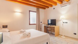 Une chambre d’hôtel avec un lit, un bureau, une télévision et une lampe.