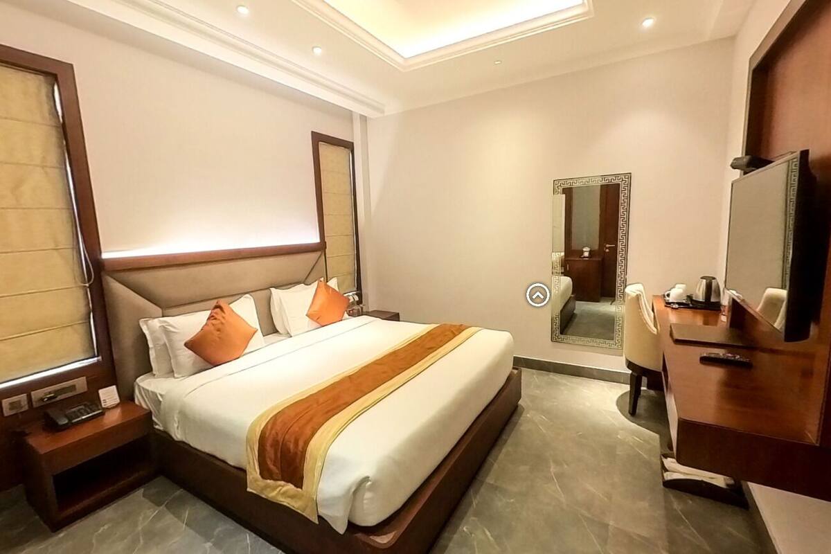 Une chambre d’hôtel avec un lit, une table de chevet, une télévision et un miroir.