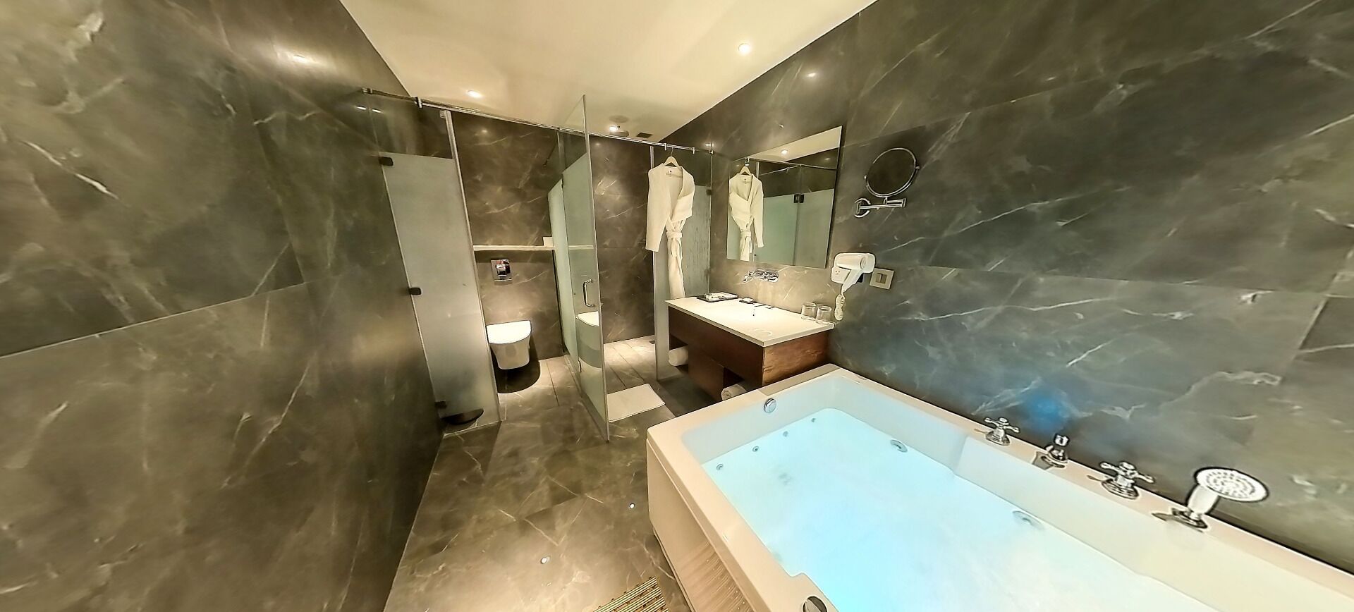 Un bany modern amb una banyera gran, un lavabo amb mirall i un suport per a tovalloles.