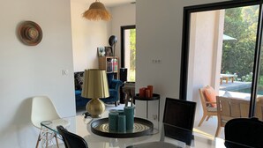 A modern living room with a glass dining table, black chairs, a blue sofa, and a bookshelf. - Nice 4-Bedroom California-Style Villa (Nice)