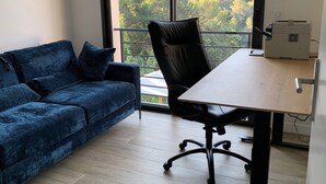 A room with a blue sofa, a black office chair, a wooden table, and a printer. - Nice 4-Bedroom California-Style Villa (Nice)