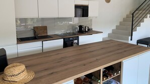 A modern kitchen with white cabinets, a wooden countertop, and a built-in microwave. - Nice 4-Bedroom California-Style Villa (Nice)