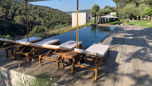 A poolside area with wooden loungers and umbrellas, surrounded by a wooden deck and a view of a hillside. - Nice 4-Bedroom California-Style Villa (Nice)