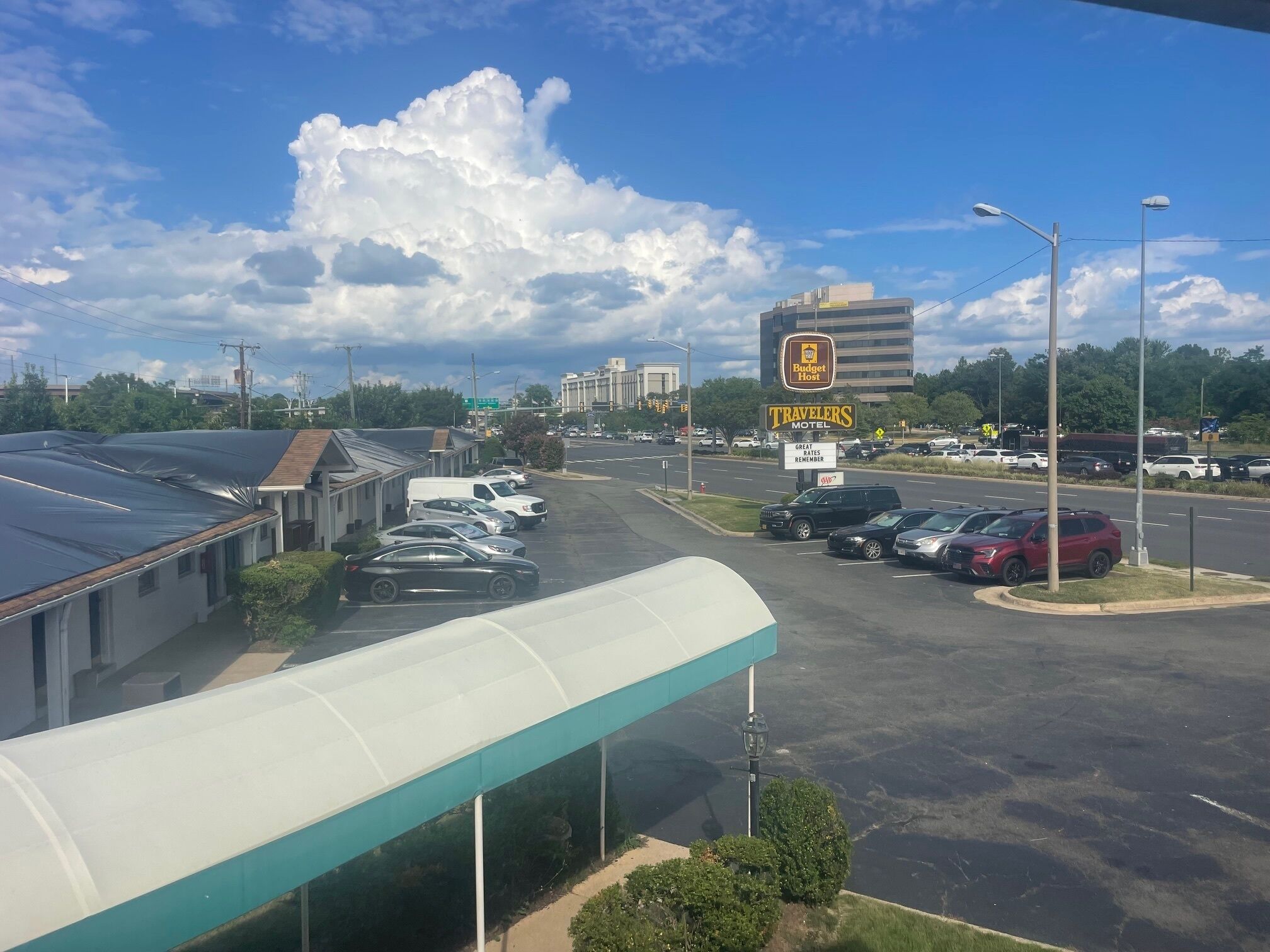 A motel with a covered parking area, a sign for Budget Host, and a Travelers Motel sign.